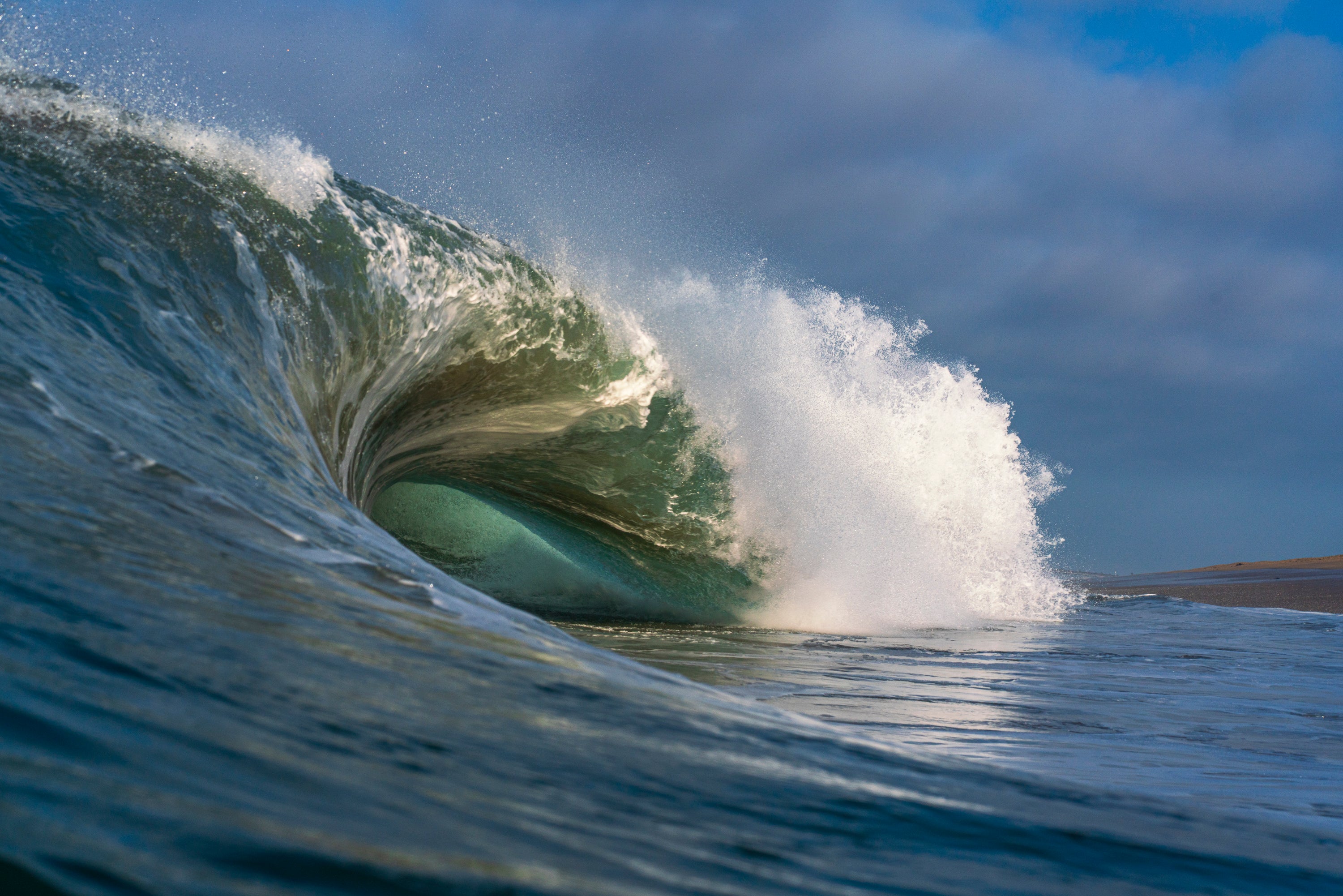 Large wave curling over itself with water spray against a blue sky. Cylinders, The Wedge, Newport Beach, California.