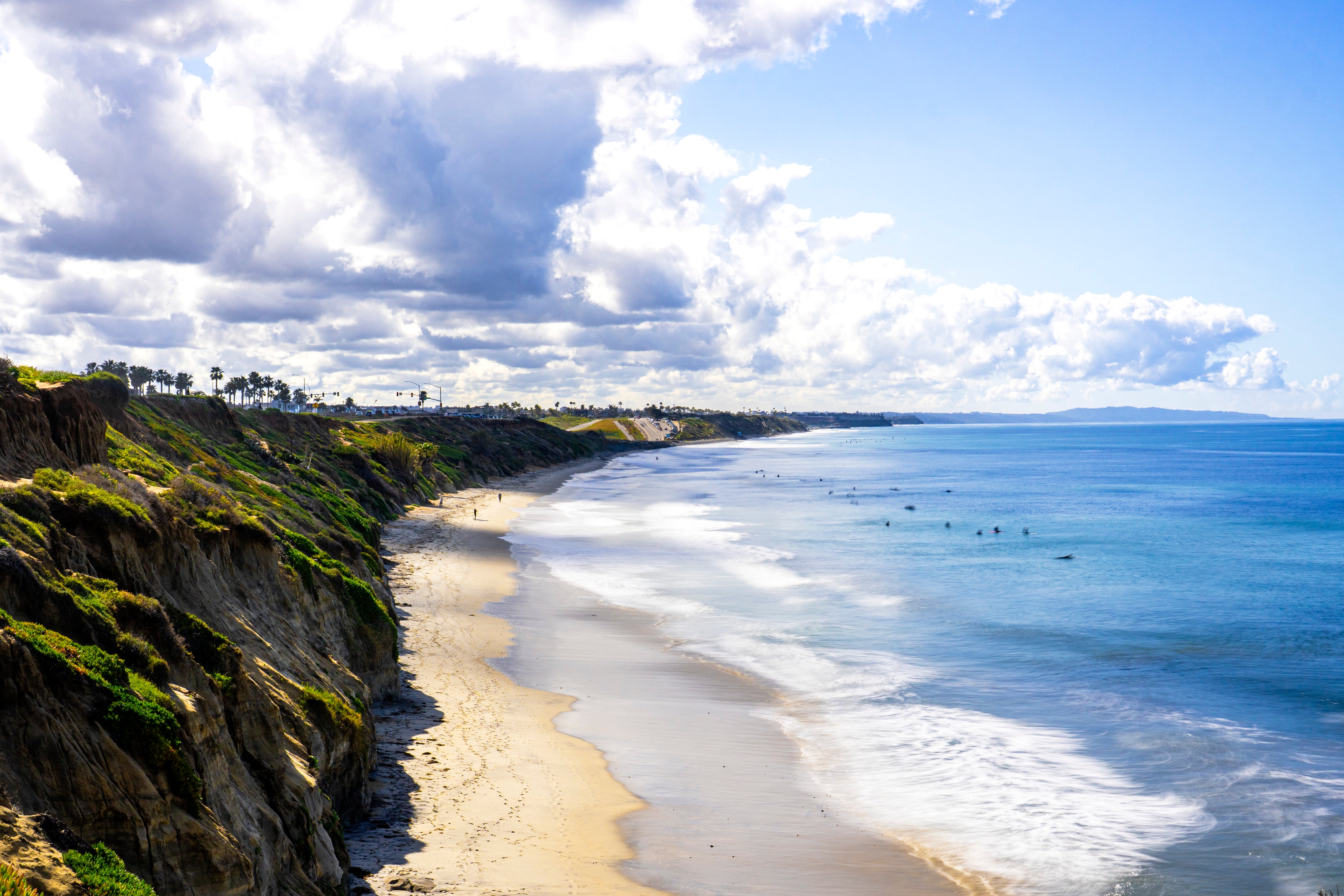 Carlsbad beach scene with cliffs and ocean under a cloudy sky.