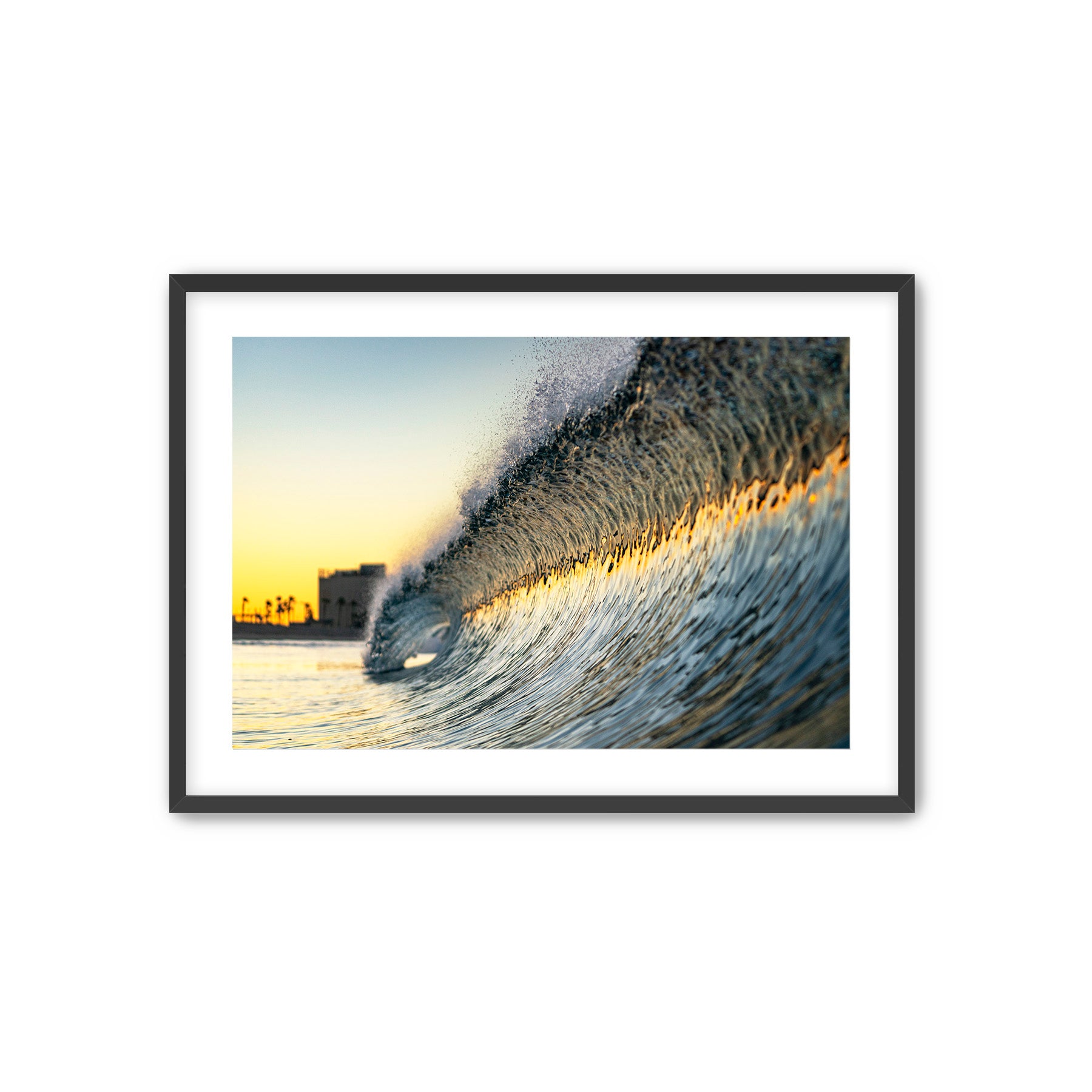 Framed photograph of a colorful wave at sunrise with the partially deconstructed Carlsbad power plant in the background.