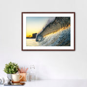 Framed photograph of a colorful wave crashing on South Carlsbad State beach with office items below. 