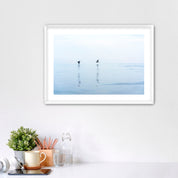 Framed artwork of two pelicans over water in Carlsbad, California, placed over a desk.