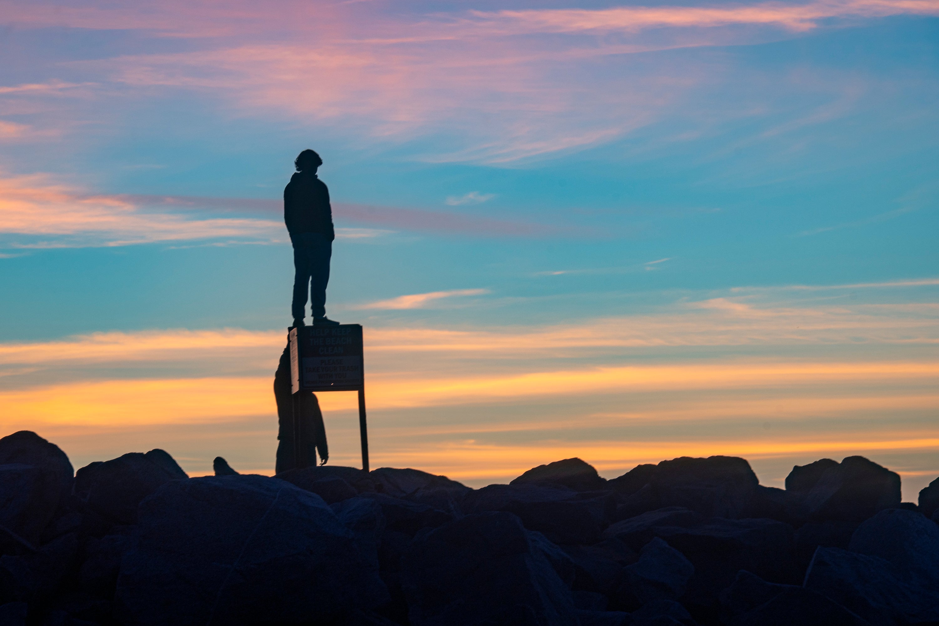 Young man standing on a sign at The Wedge jetty in Newport Beach, California. 