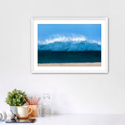 Framed artwork of a light blue wave on a beach with office items below. 