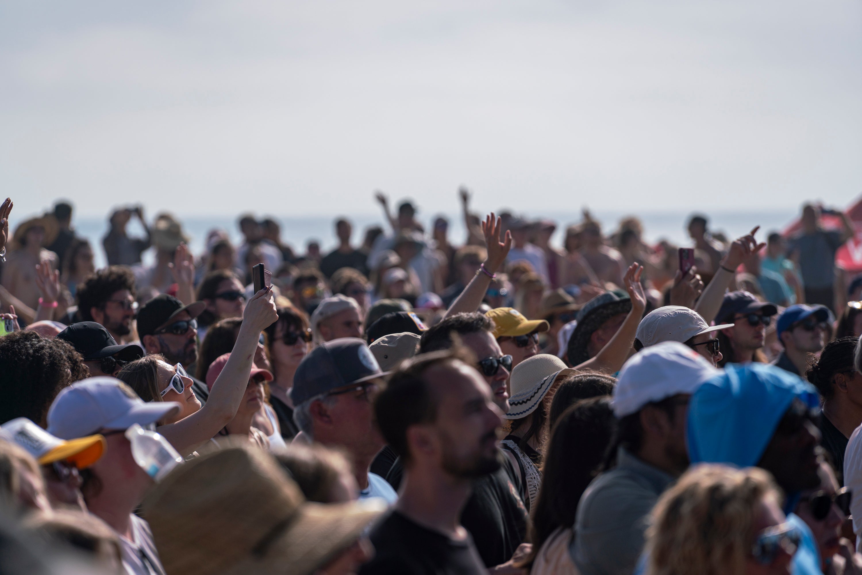 Large crowd of people at an outdoor event with a clear sky.