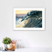 Framed photograph of a wave like a jewel on a wall above a desk with office supplies.