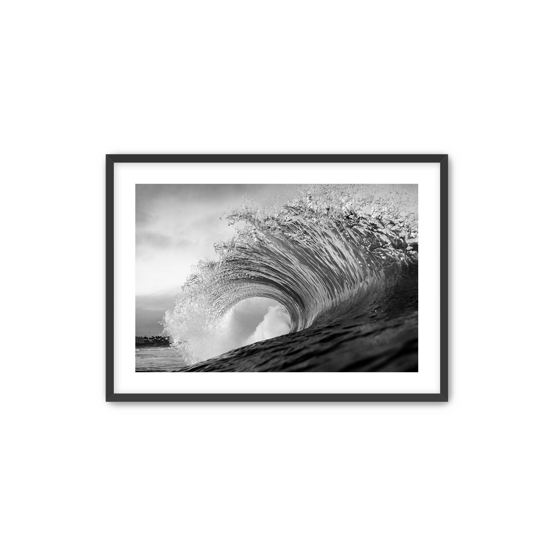 Framed black and white wave art print shot next to the Pacific Coast Highway at South Carlsbad State Beach in Carlsbad, California on a wall above a desk with office supplies.