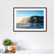 Framed photograph of a crisp morning wave in Carlsbad on a wall above a desk with office supplies.
