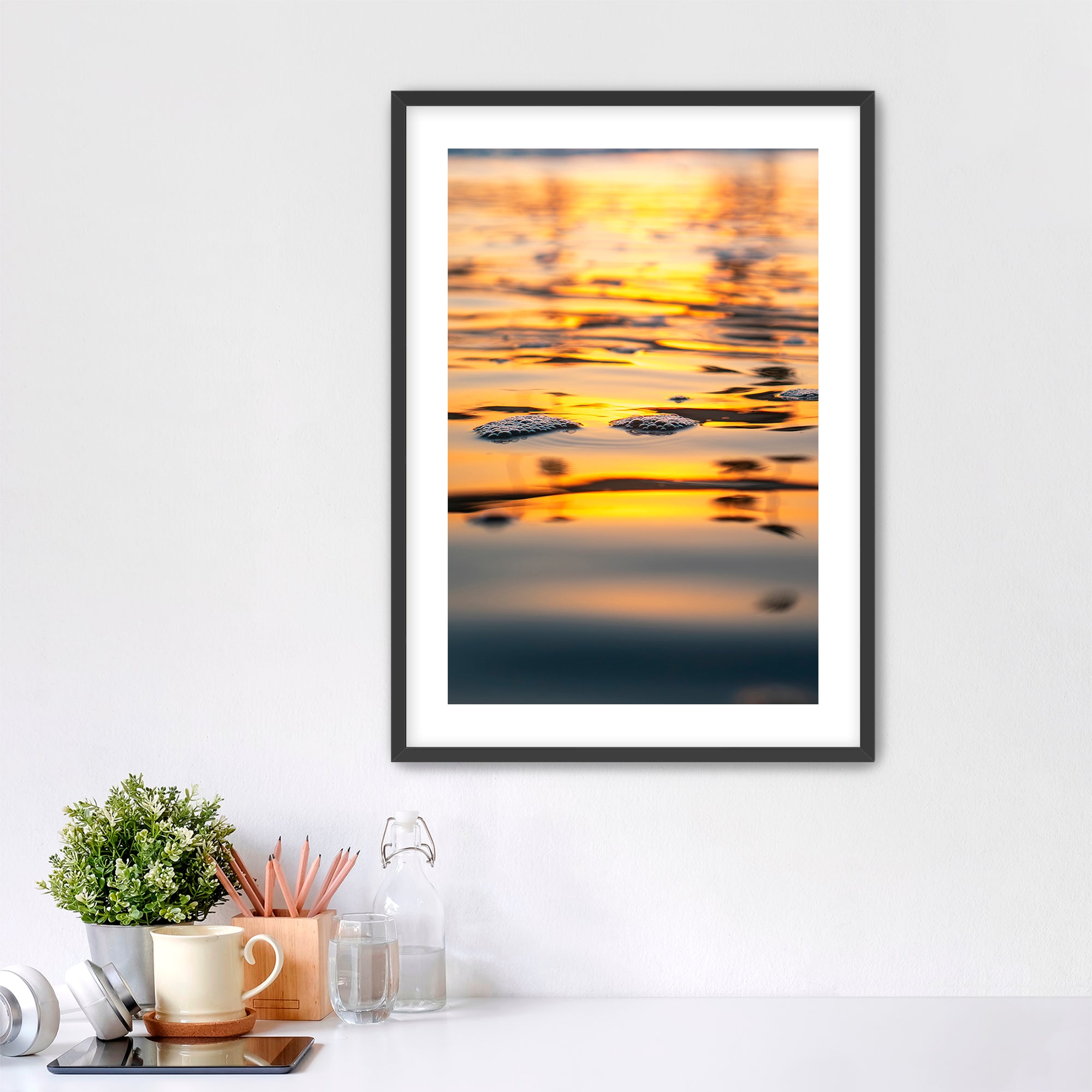 Framed artwork of a sunrise reflection  of palm trees on water in a home office setting.
