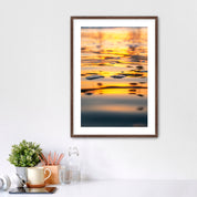 Framed artwork of a sunrise reflection  of palm trees on water in a home office setting.