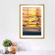 Framed artwork of a sunrise reflection  of palm trees on water in a home office setting.