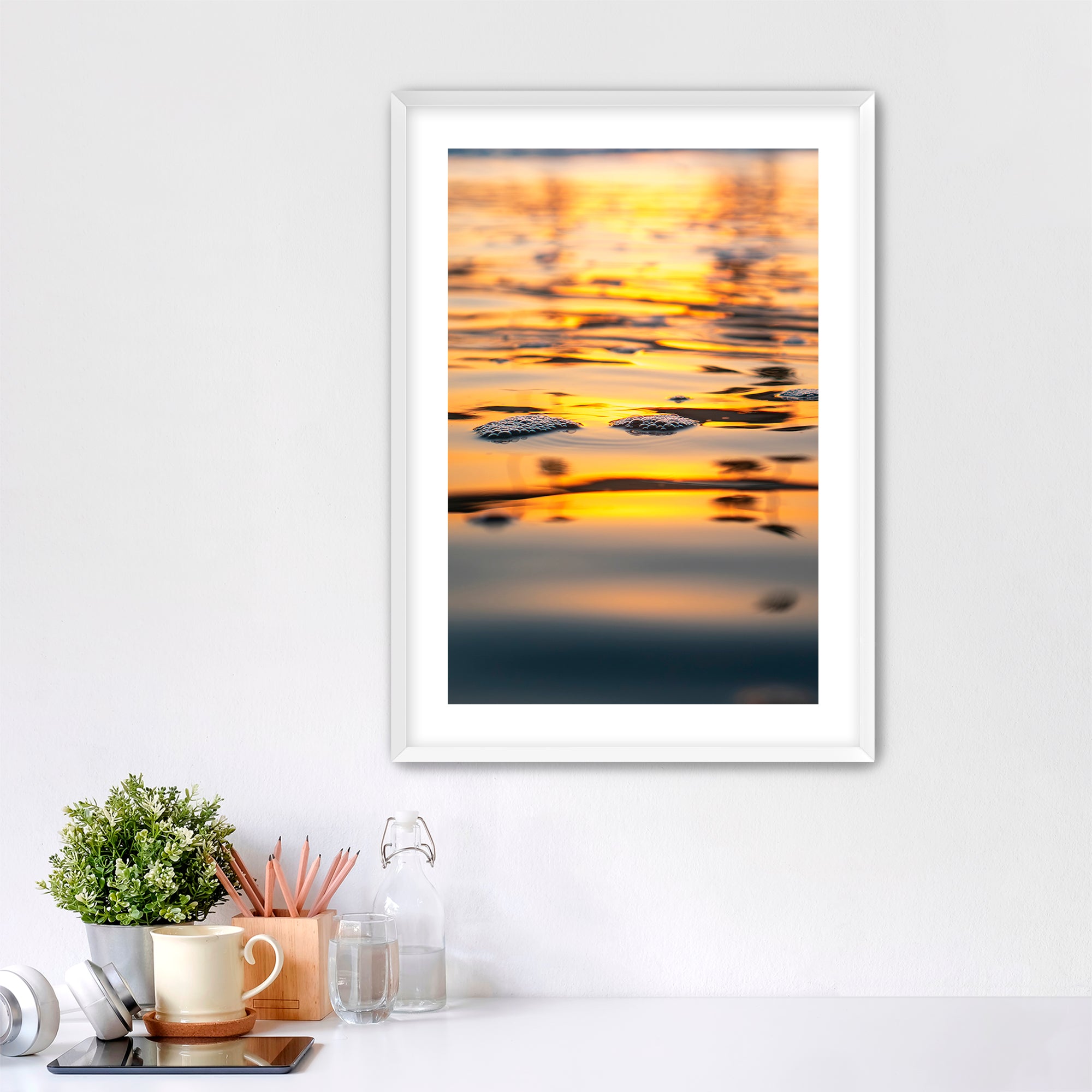 Framed artwork of a sunrise reflection  of palm trees on water in a home office setting.