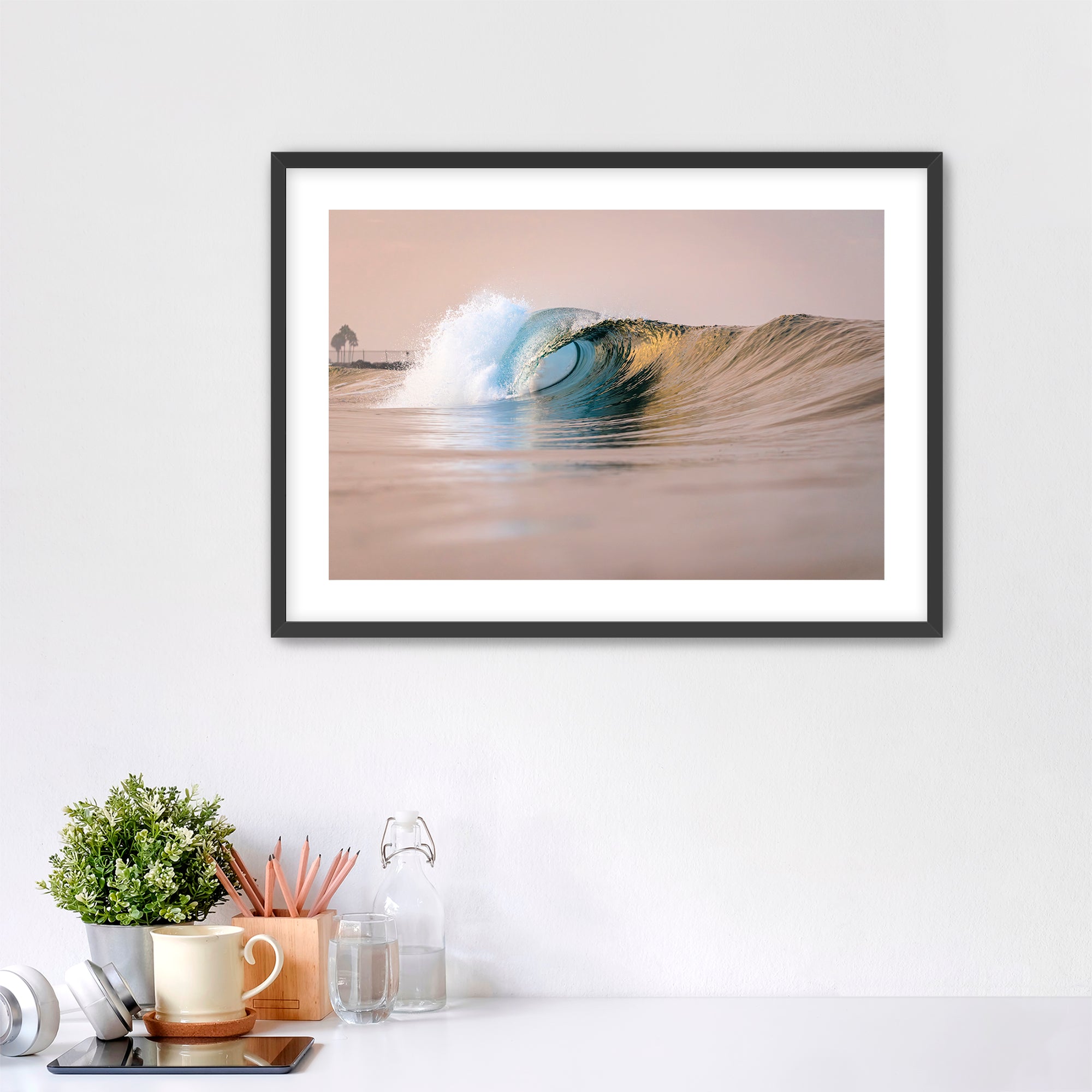 Framed artwork of a warm wave on a wall above a desk with office supplies. South Carlsbad State Beach, Carlsbad, California. 