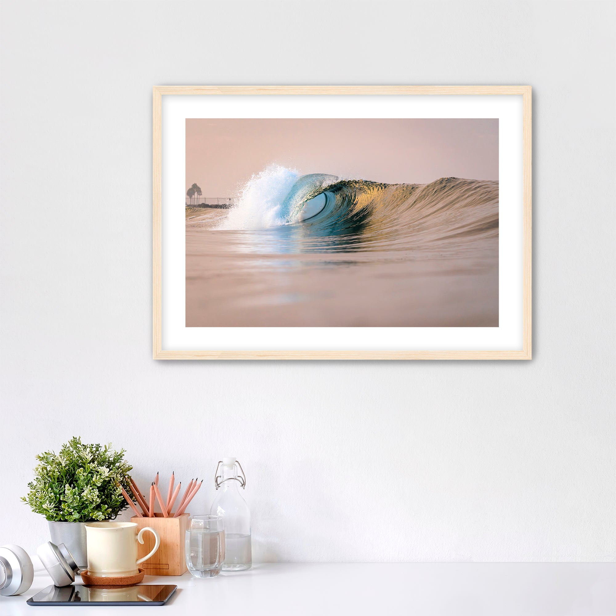 Framed artwork of a warm wave on a wall above a desk with office supplies. South Carlsbad State Beach, Carlsbad, California. 