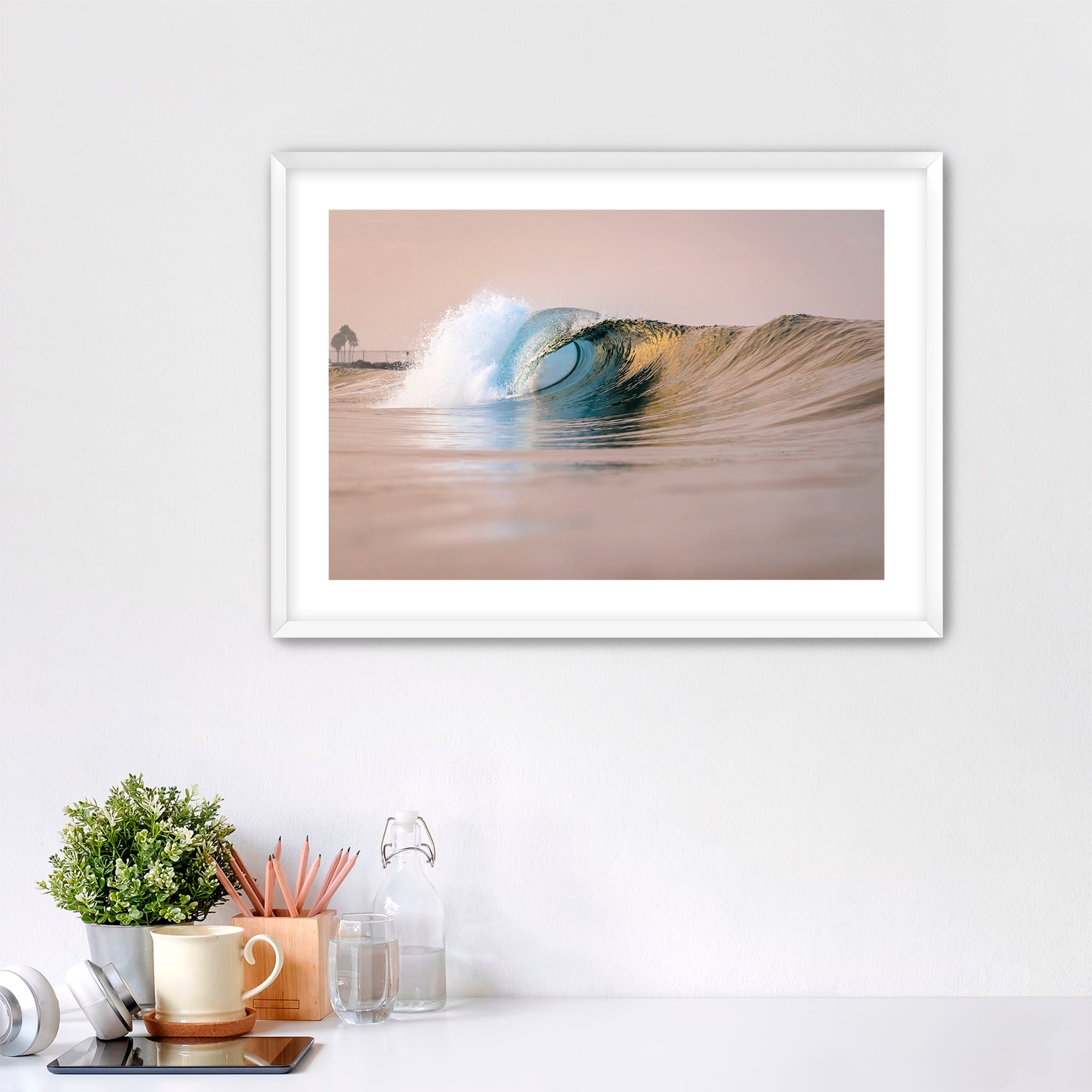 Framed artwork of a warm wave on a wall above a desk with office supplies. South Carlsbad State Beach, Carlsbad, California. 