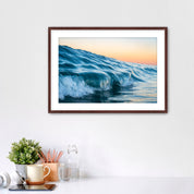 Framed photograph of a wave at Tamarack beach on a wall above a desk with office supplies.