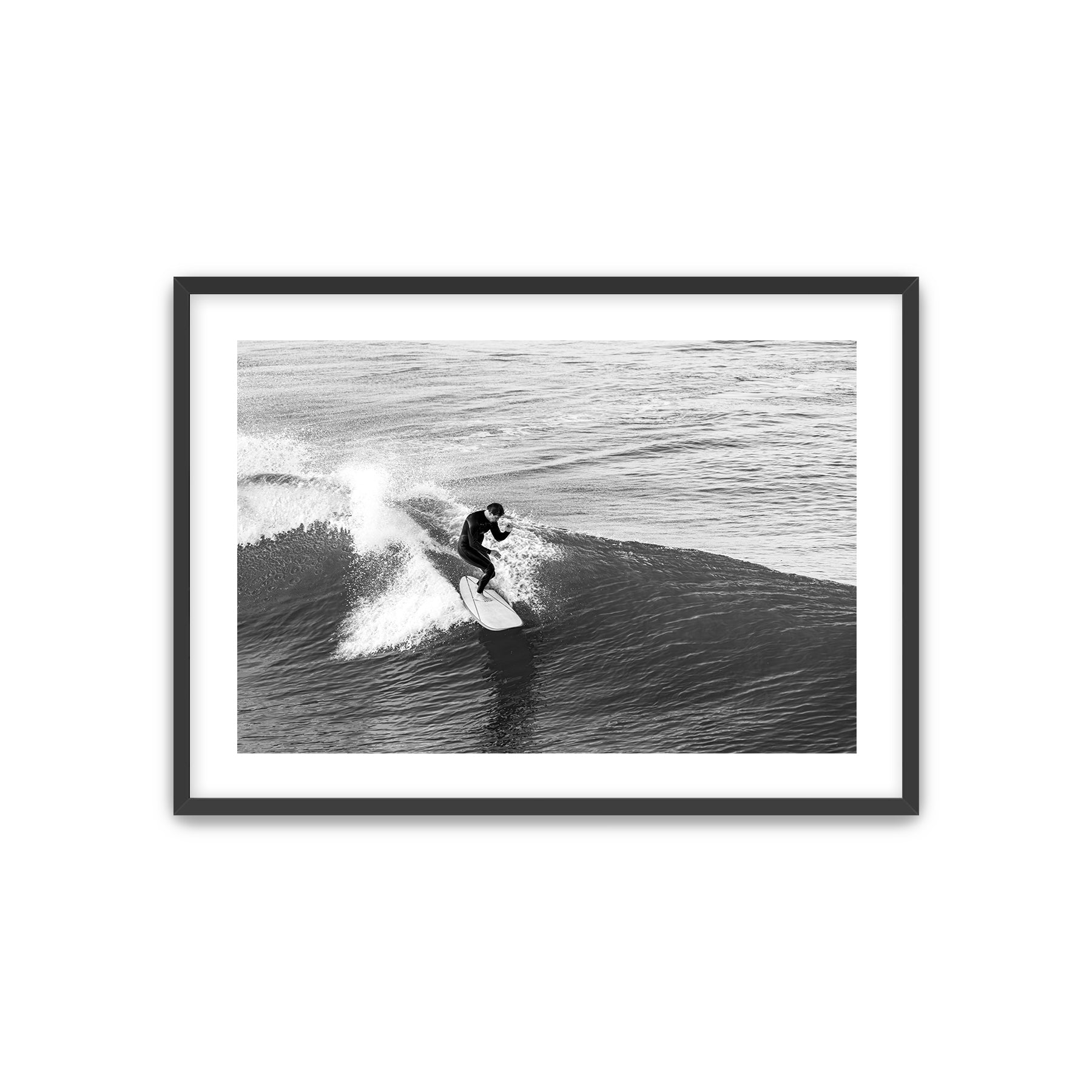 Framed black and white photograph of a surfer riding a wave.