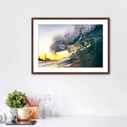Framed photograph of a wave at sunrise on a wall above a desk with office supplies.