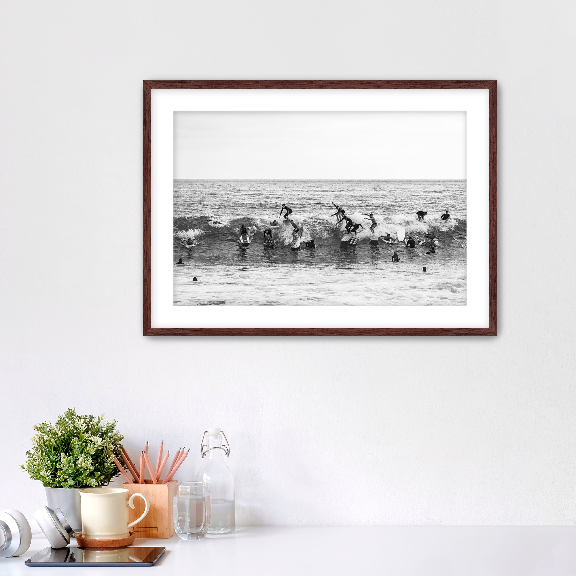 Black and white framed photo of many surfers riding one wave at Tamarack Beach in Carlsbad. 