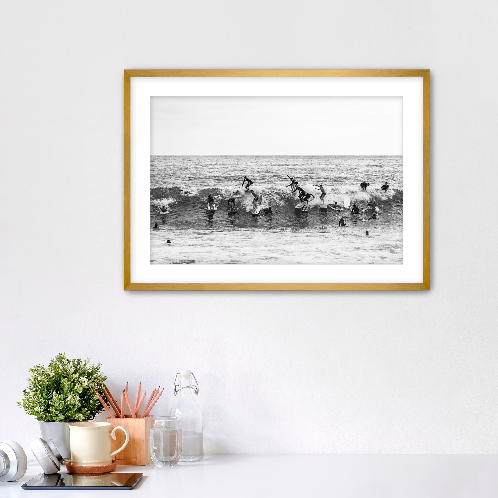 Black and white framed photo of many surfers riding one wave at Tamarack Beach in Carlsbad. 