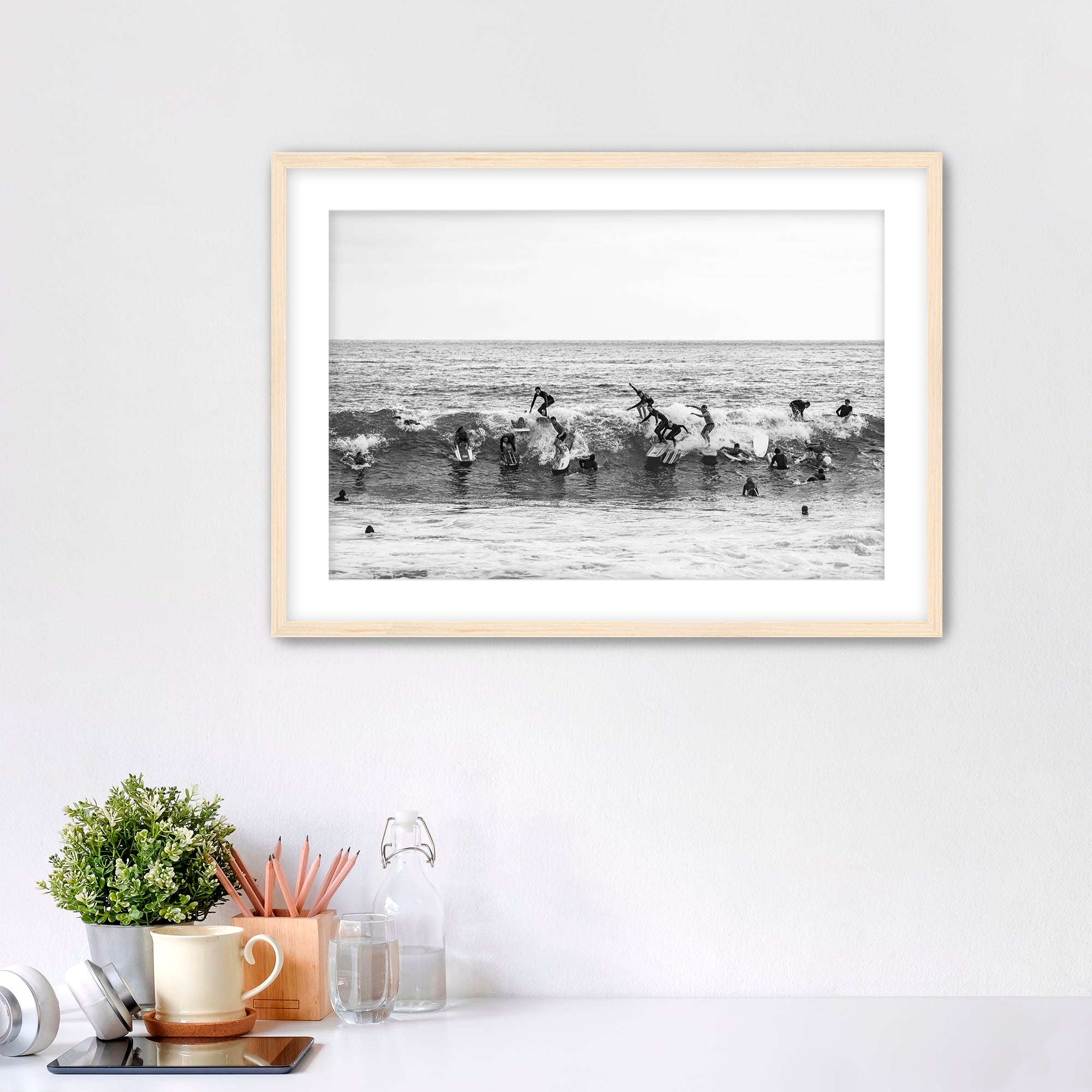 Black and white framed photo of many surfers riding one wave at Tamarack Beach in Carlsbad. 