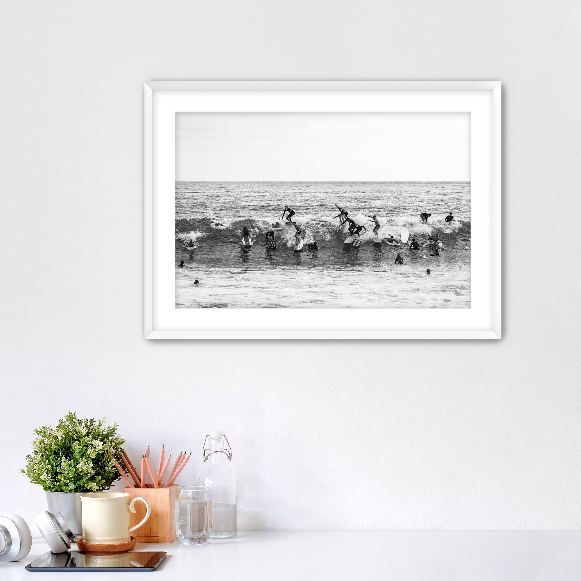 Black and white framed photo of many surfers riding one wave at Tamarack Beach in Carlsbad. 