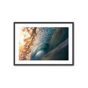 Framed photograph of a wave with sunlight filtering through.