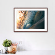 Framed photograph of the inside of a barreling wave on a white wall above a desk with office supplies.