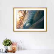 Framed photograph of the inside of a barreling wave on a white wall above a desk with office supplies.
