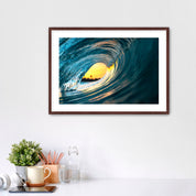 Framed artwork photo of a breaking wave with the orange sunrise sky in the middle. 