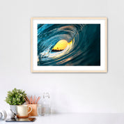 Framed artwork photo of a breaking wave with the orange sunrise sky in the middle. 