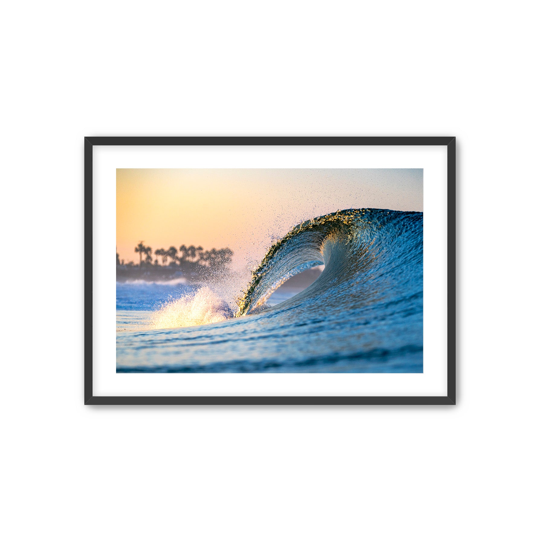 Framed photograph of a wave at sunset with palm trees in the background. 