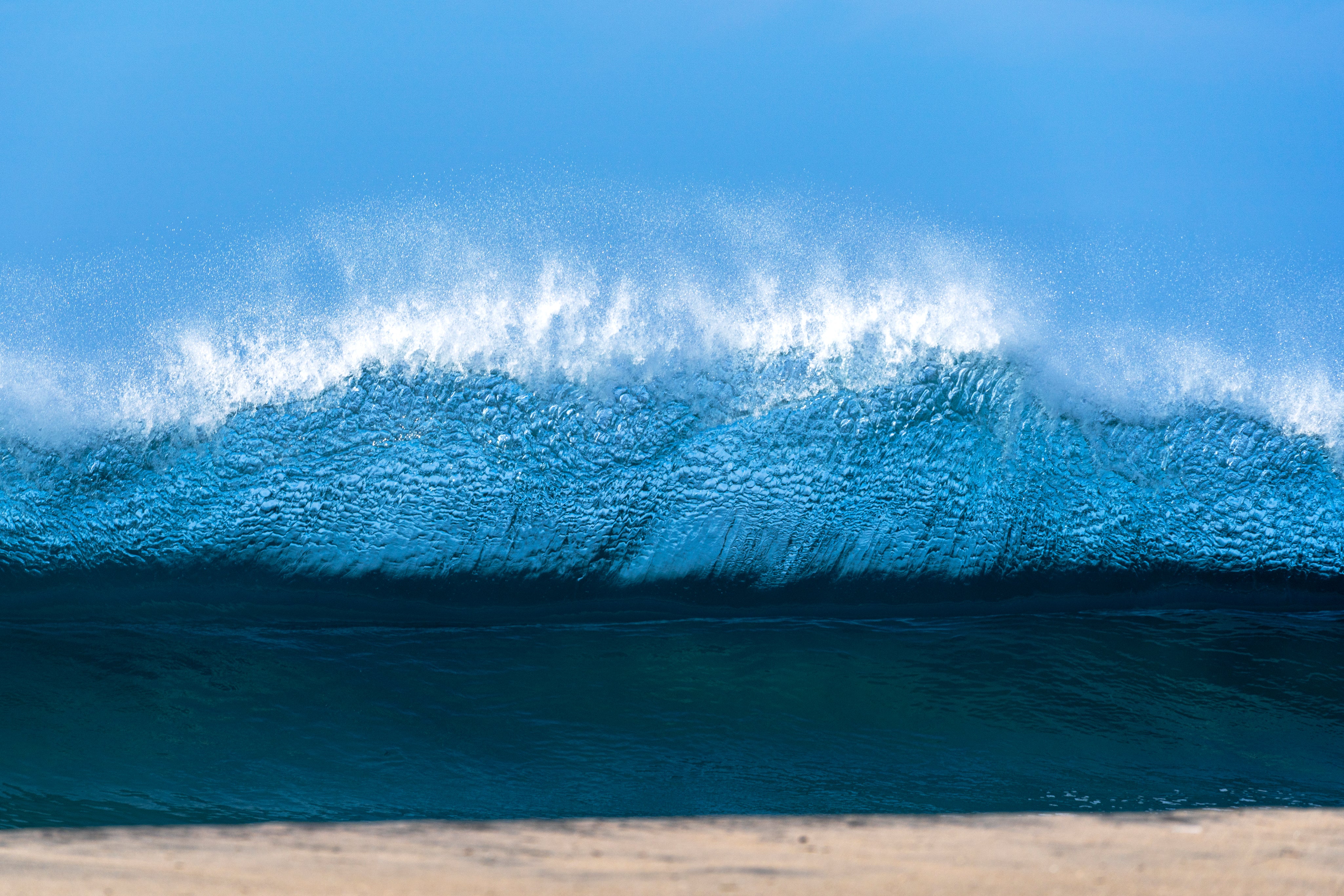 Framed artwork of a light blue wave on a beach.  